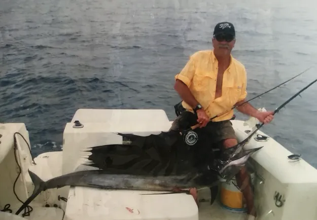 Holding caught swordfish on stern of boat